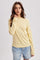 woman wearing a yellow striped long sleeve top with a relaxed fit and denim shorts