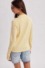 woman wearing a yellow and white striped long sleeve top paired with denim shorts, viewed from the back