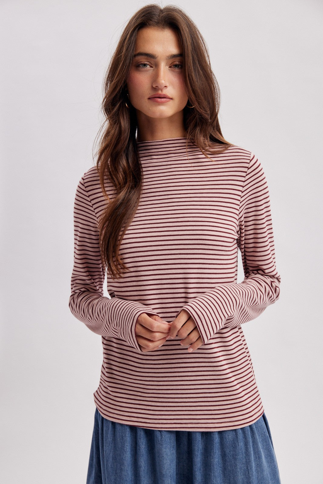 woman wearing a pink and white striped long sleeve top with a high neckline and relaxed fit