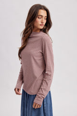 woman wearing a maroon and cream striped long sleeve top with a high neckline and a denim skirt