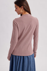 woman wearing a long sleeve striped top in burgundy and pink with a round neckline, styled with a denim skirt