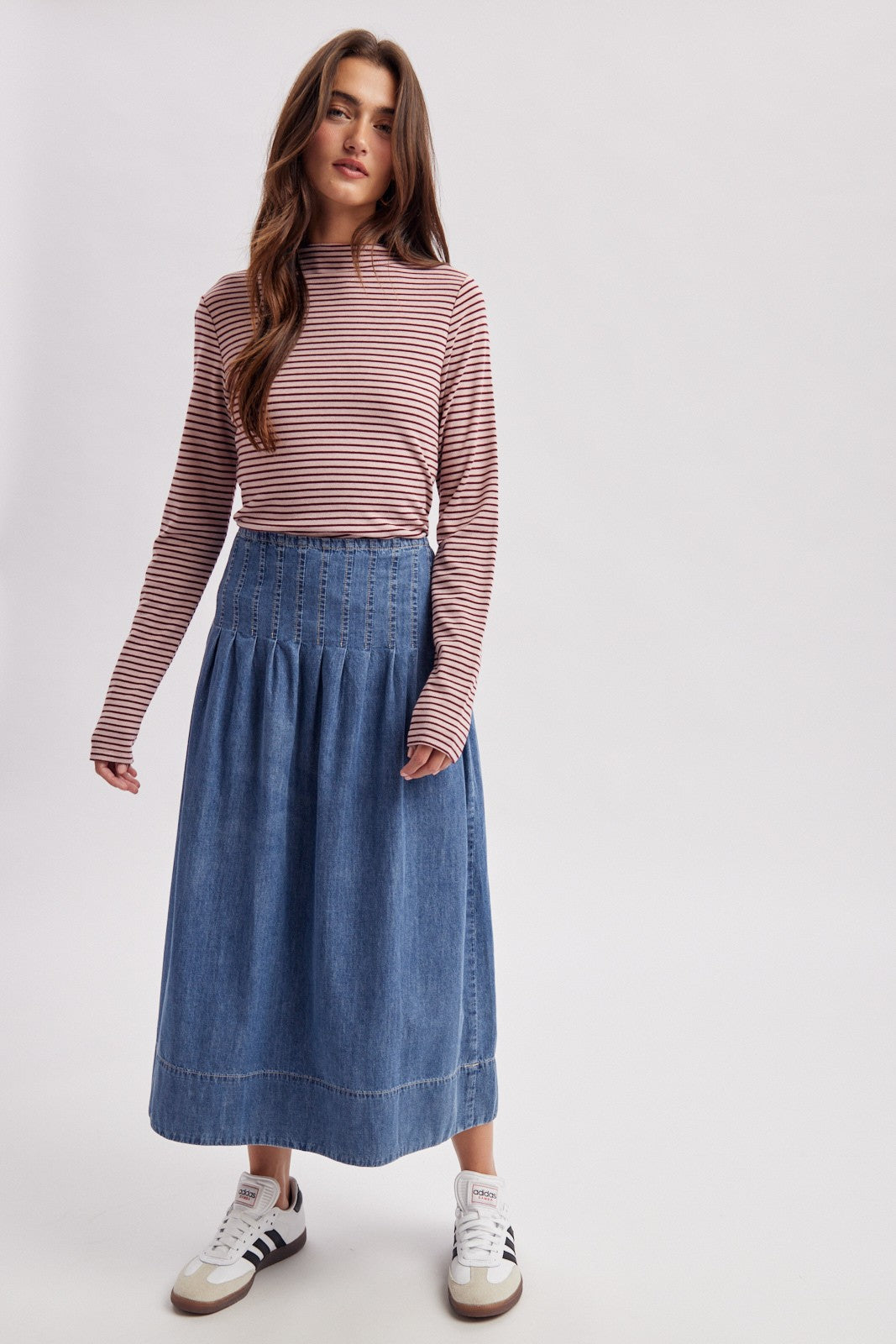 woman wearing a striped long sleeve top with a denim midi skirt and sneakers
