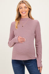 woman wearing a pink and burgundy striped maternity top with a mock neck and holding her baby bump