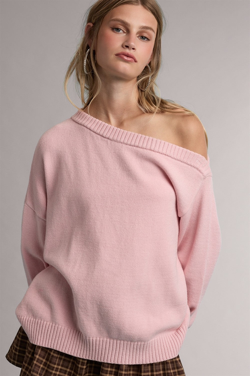 woman wearing a soft pink off-shoulder sweater with a relaxed fit and ribbed hem