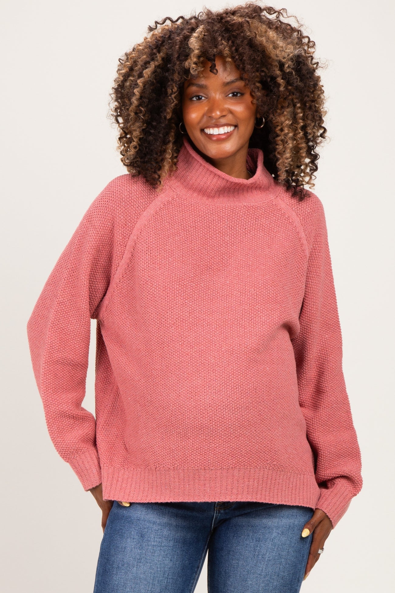 woman wearing a dusty rose oversized turtleneck maternity sweater with long sleeves and a relaxed fit, baby bump visible