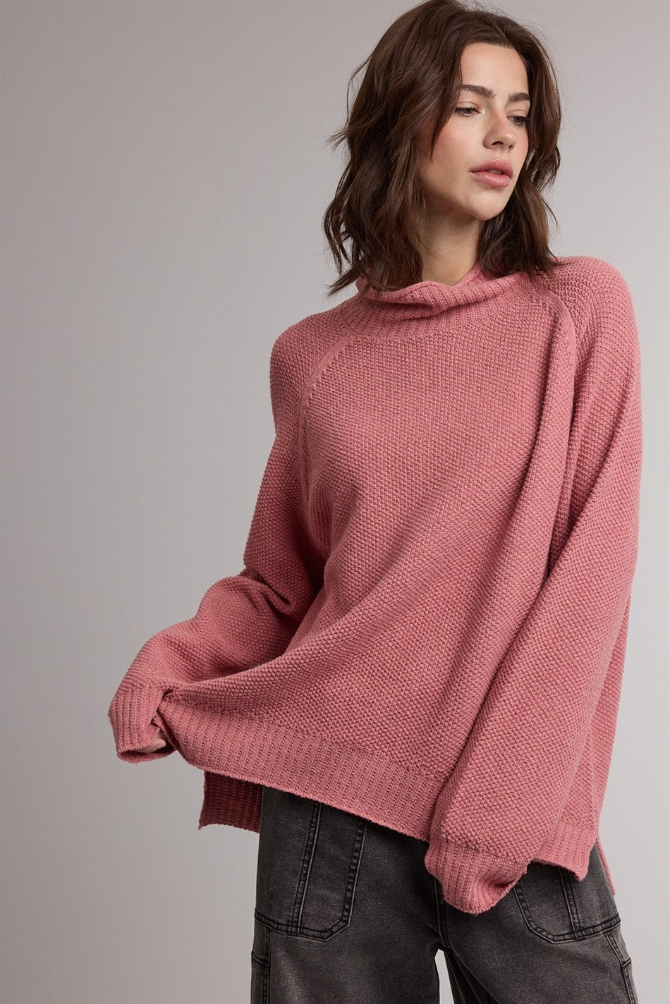 woman wearing a dusty pink oversized knit sweater with a cowl neck and long sleeves paired with casual pants