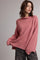 woman wearing a dusty pink oversized knit sweater with a cowl neck and long sleeves paired with casual pants