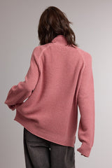 woman wearing a pink chunky knit sweater with a high collar and relaxed fit, shown from the back