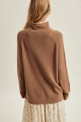 woman wearing a brown knit sweater with a high collar, seen from the back over a floral dress