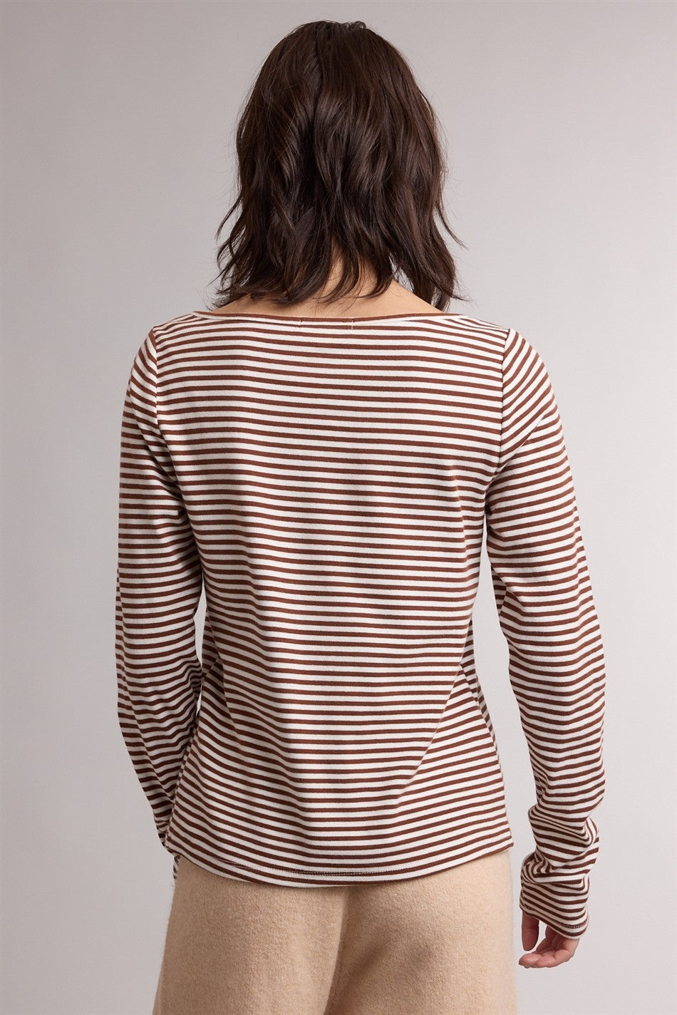 woman wearing a brown and cream striped long sleeve top, showing the back view