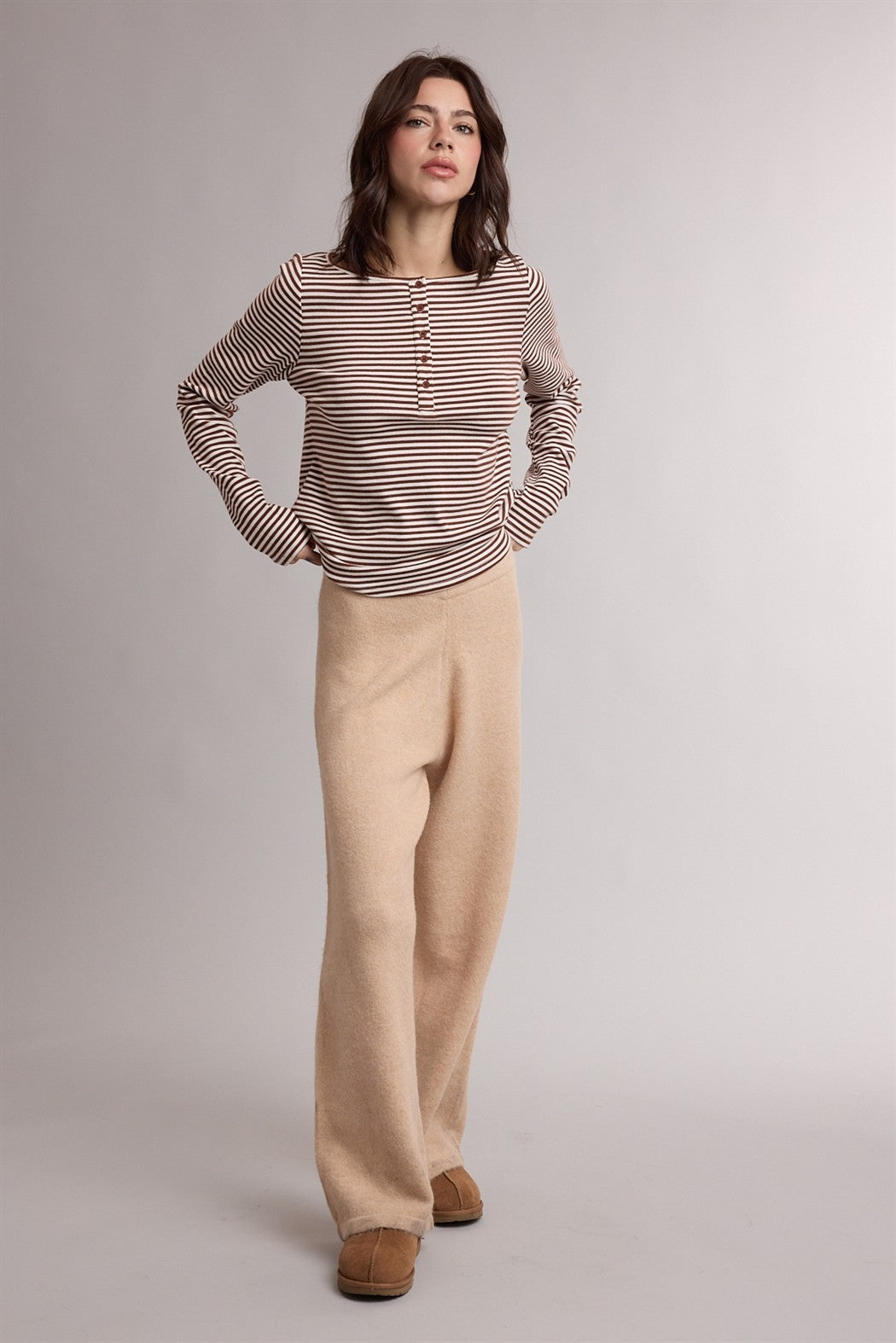 woman wearing a cream and burgundy striped long sleeve top and beige wide-leg pants