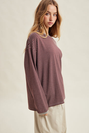 woman wearing a maroon and cream striped long sleeve top with a relaxed fit and round neckline