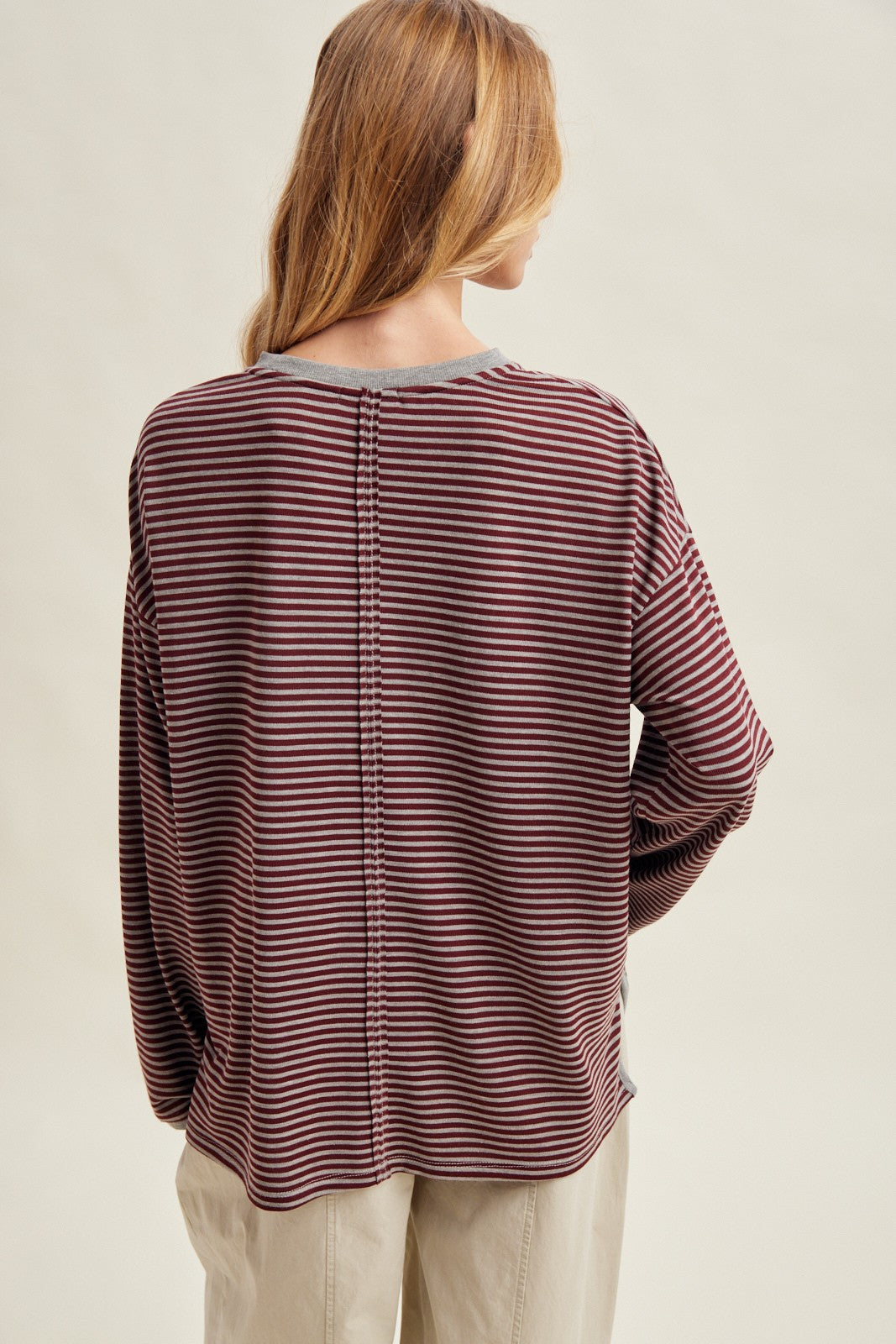 woman wearing a maroon and gray striped long sleeve top showing a relaxed fit and back seam detail