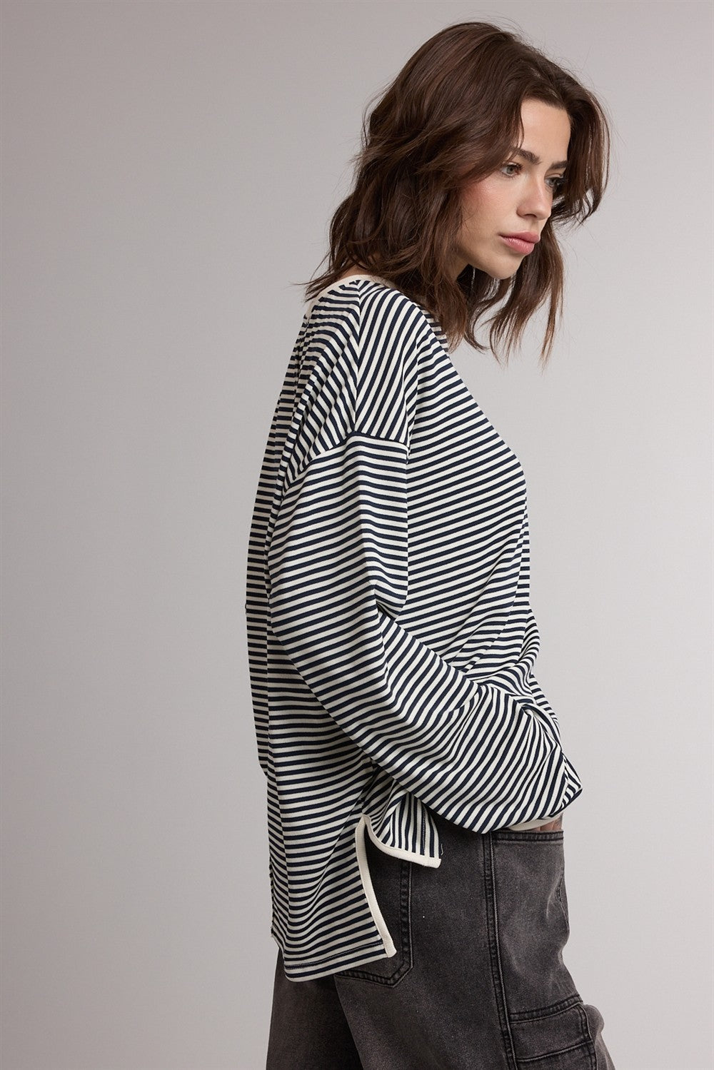 woman wearing a black and white striped long sleeve top with a relaxed fit and side slits, paired with dark jeans