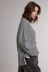 woman wearing a black and white striped long sleeve top with a relaxed fit and side slits, paired with dark jeans