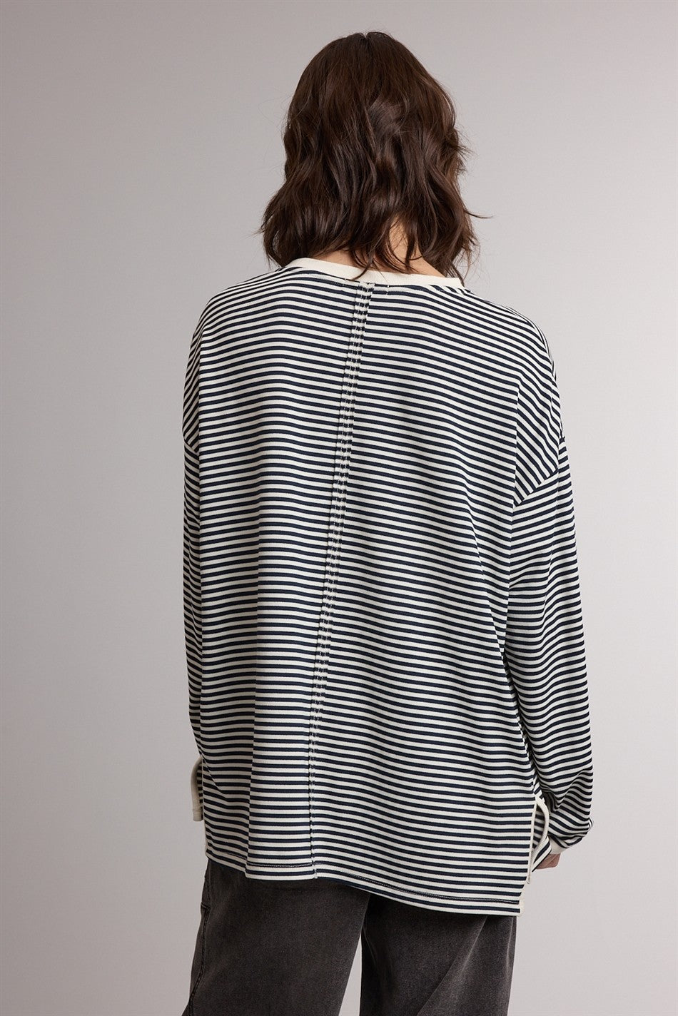woman wearing a black and white striped long sleeve top with a relaxed fit and button detail on the back
