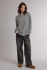 woman wearing a black and white striped oversized long sleeve top with loose gray pants and brown ankle boots