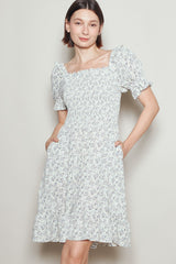 woman wearing a white floral puff sleeve dress with a smocked bodice and pockets