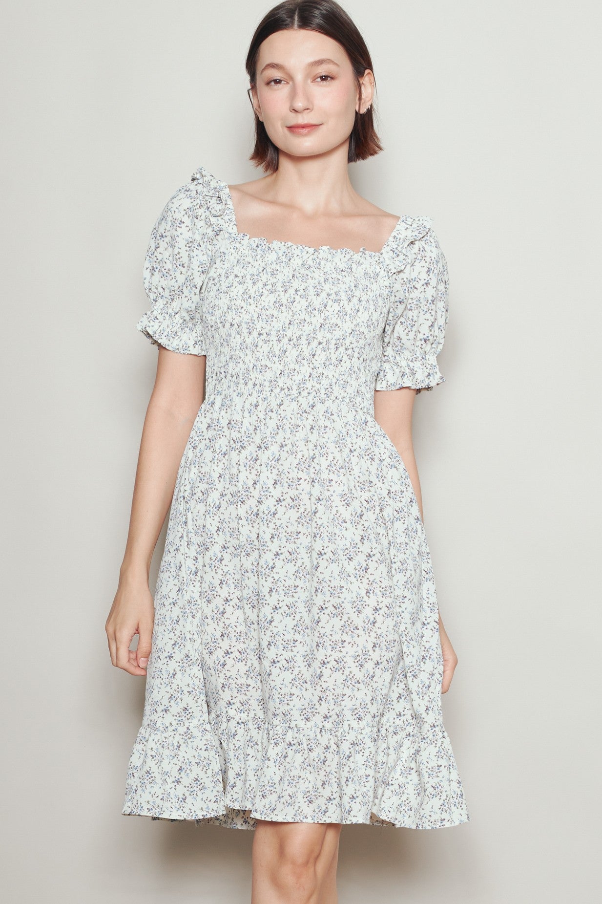 woman wearing a white floral smock dress with puff sleeves and a tiered skirt