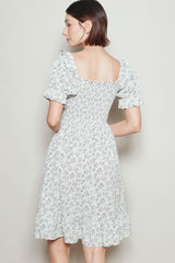 woman wearing a white floral short sleeve dress with a fitted bodice and ruffled hem