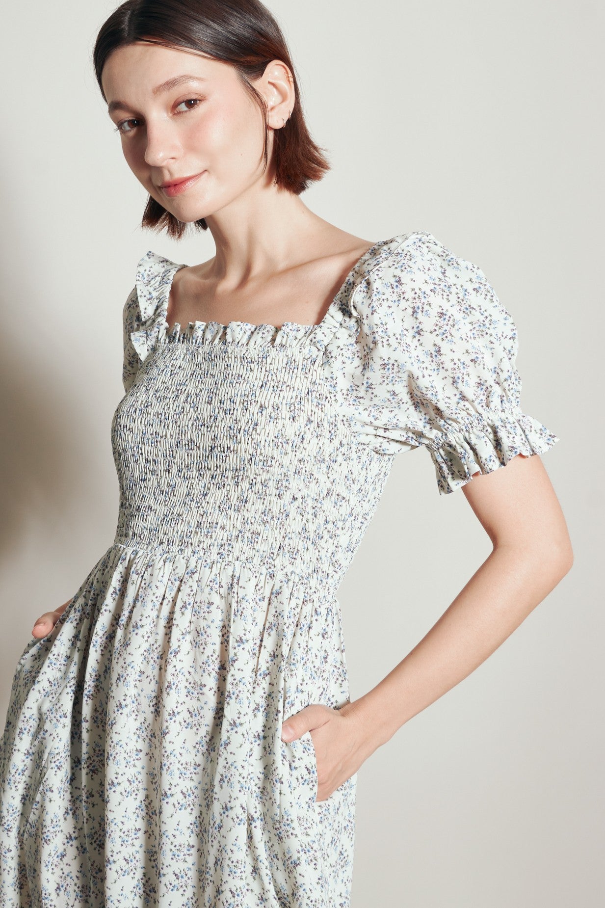 woman wearing a floral print smocked dress with puff sleeves and pockets