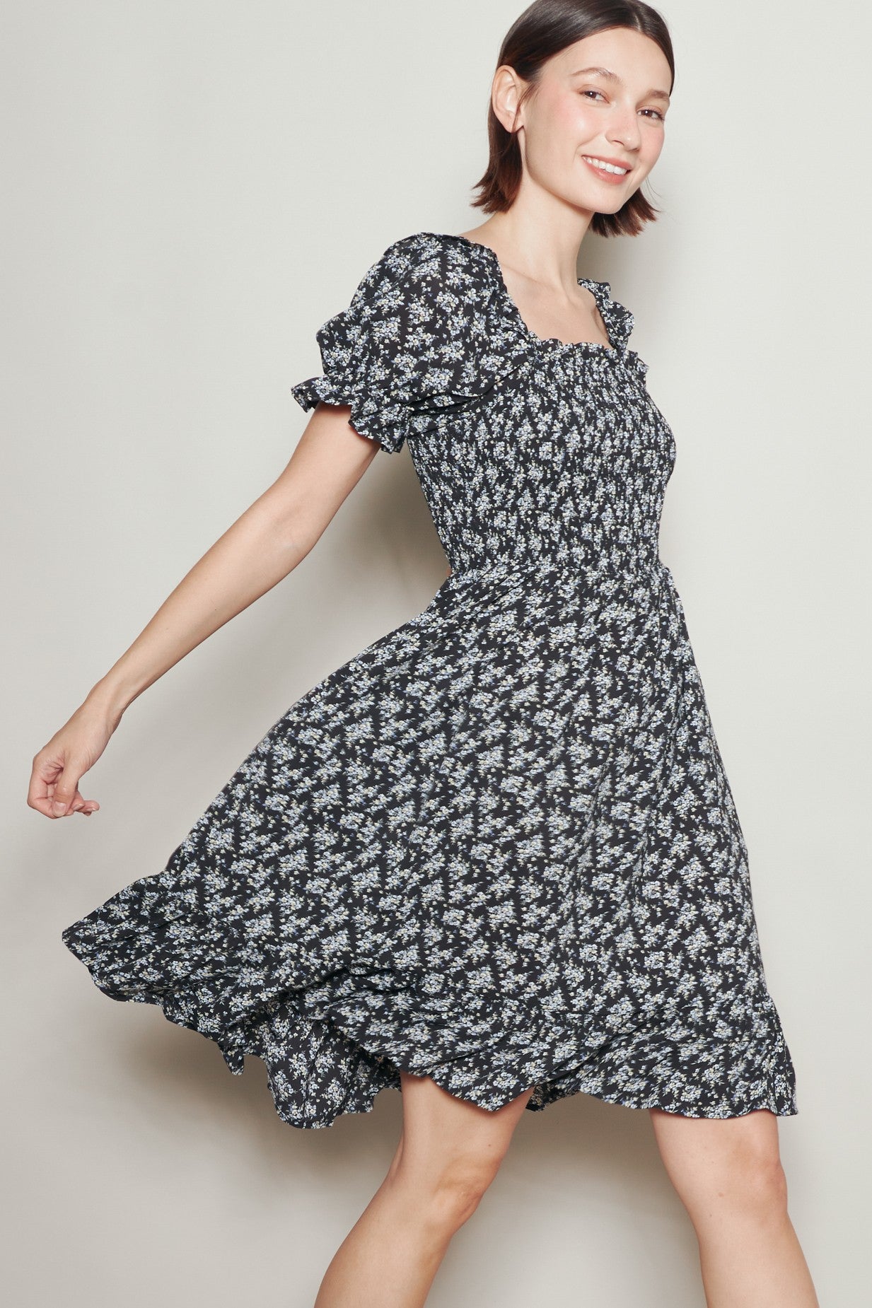 woman wearing a black floral short sleeve dress with a smocked bodice and flared skirt