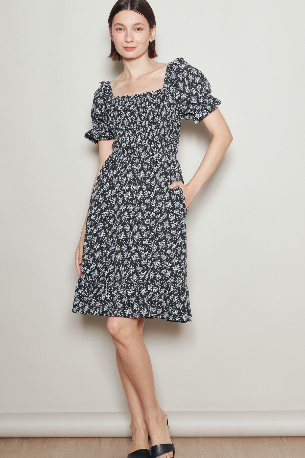 woman wearing a black floral print square neck dress with puff sleeves and pockets