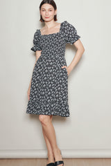 woman wearing a black floral print square neck dress with puff sleeves and pockets