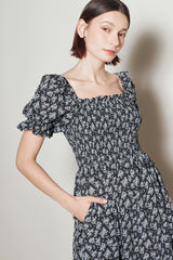 woman wearing a black floral puff sleeve dress with a square neckline and side pockets