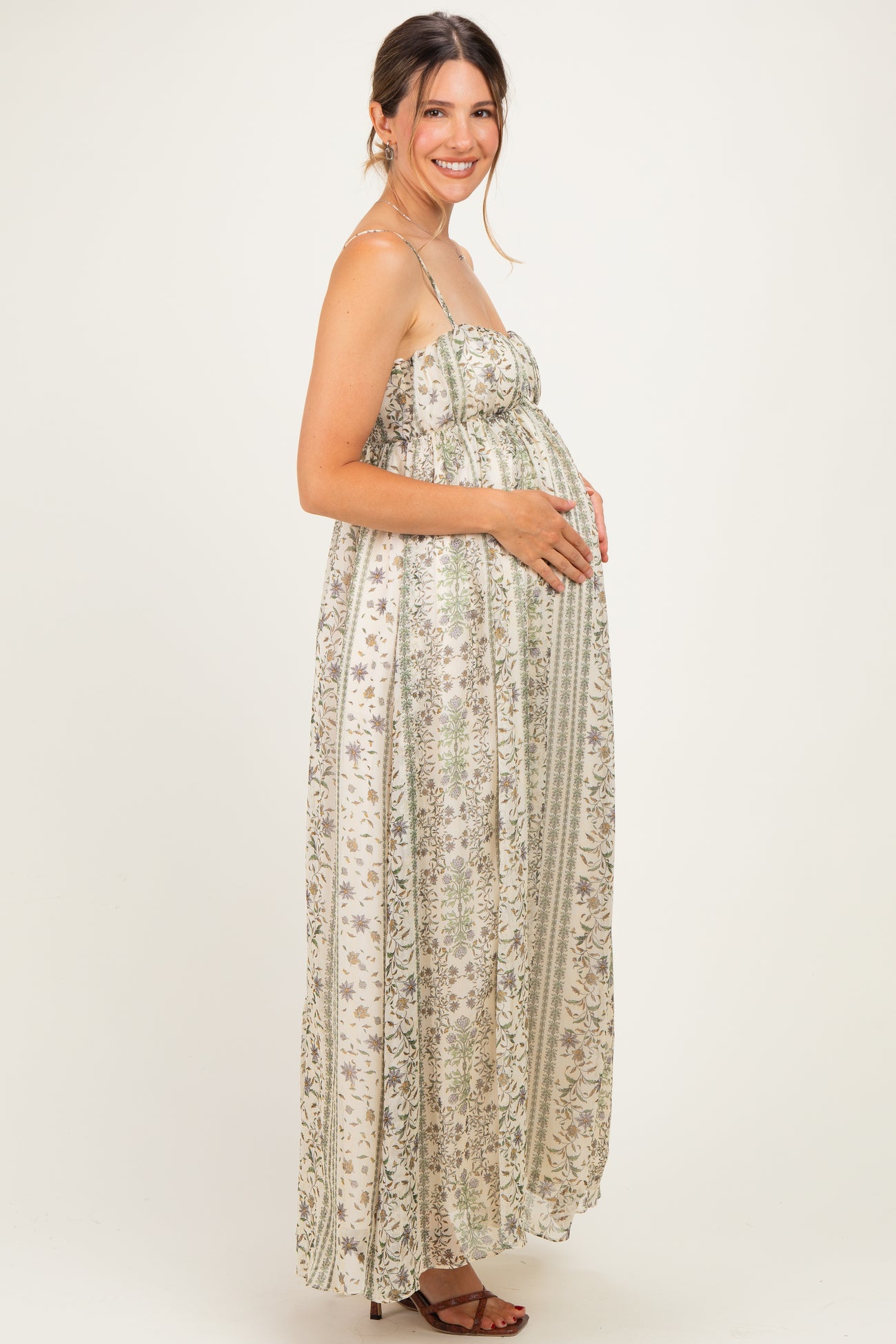 woman wearing a floral printed maternity maxi dress and gently holding her baby bump