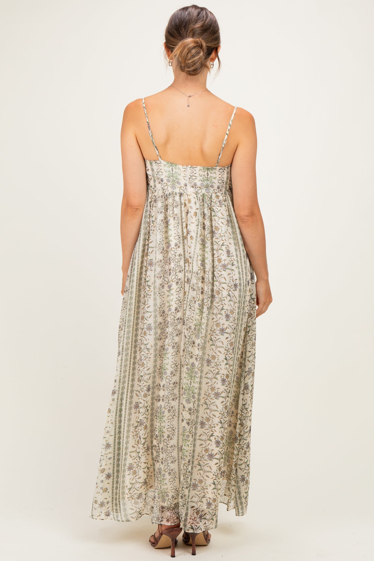 woman wearing a light floral print maternity maxi dress with spaghetti straps, showing the back view