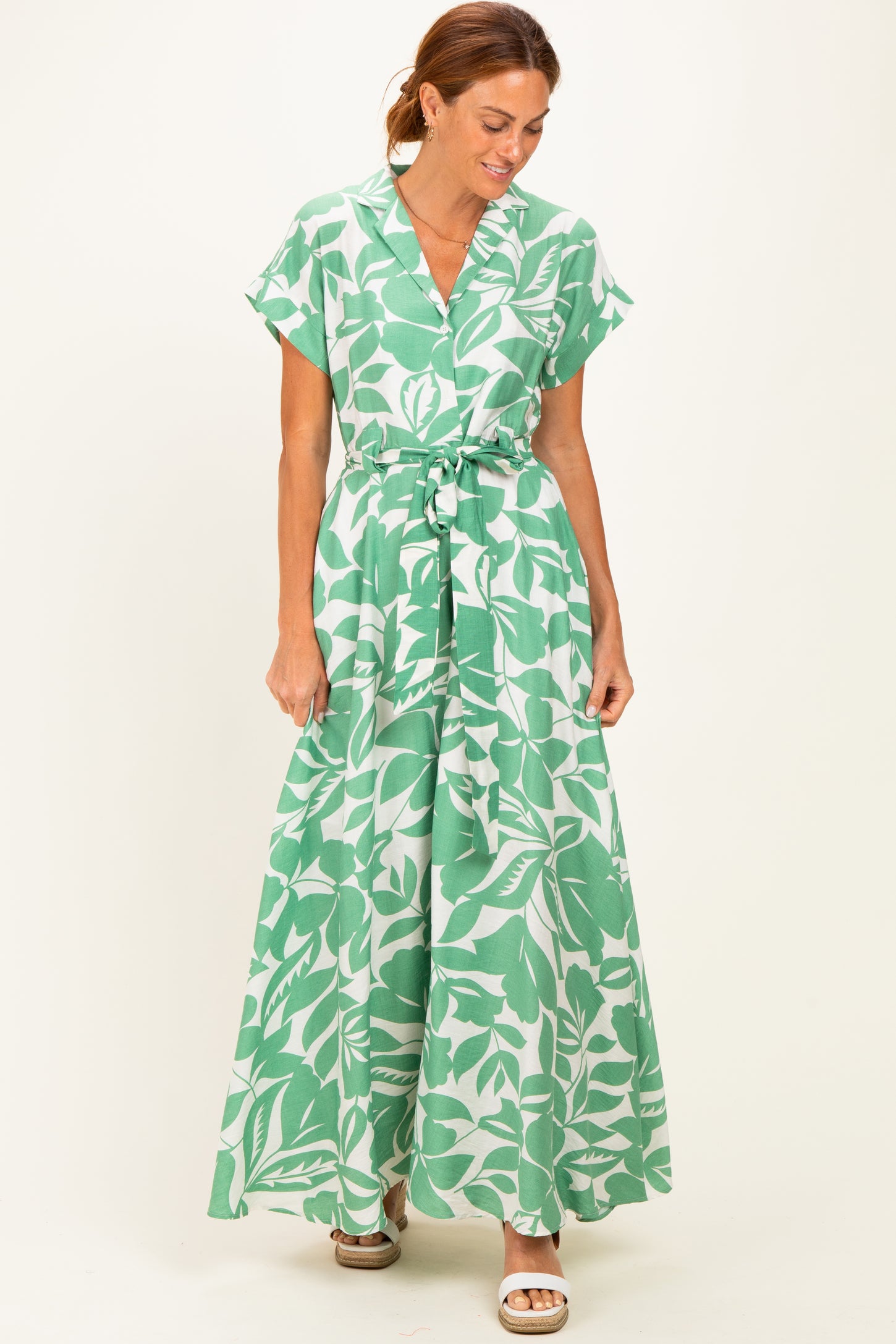 woman wearing a green floral maxi dress with short sleeves and a belted waist