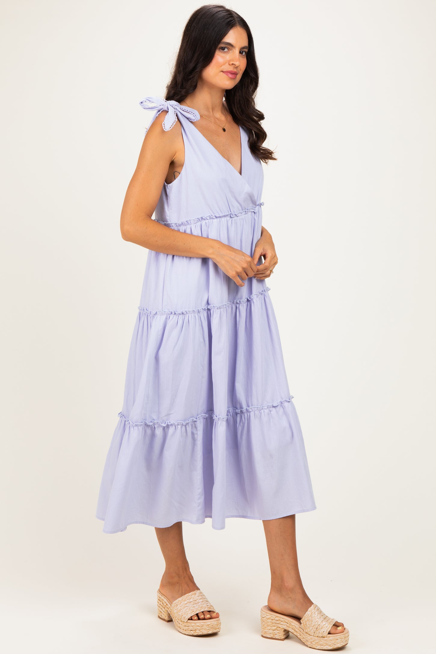woman wearing a lavender tiered maxi dress with tie shoulder straps and a plunging neckline
