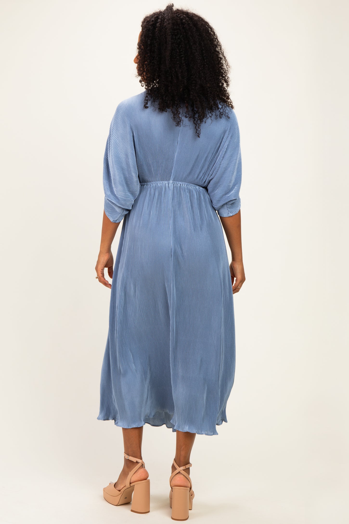 woman wearing a light blue midi dress with a cinched waist and balloon sleeves, shown from the back