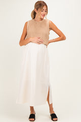 woman wearing a beige sleeveless sweater and a white maxi skirt, showing her baby bump as maternity wear