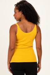 woman wearing a back view of a yellow ribbed tank top with lace detailing on the straps