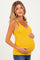 woman wearing a yellow maternity tank top with lace trim and holding her baby bump