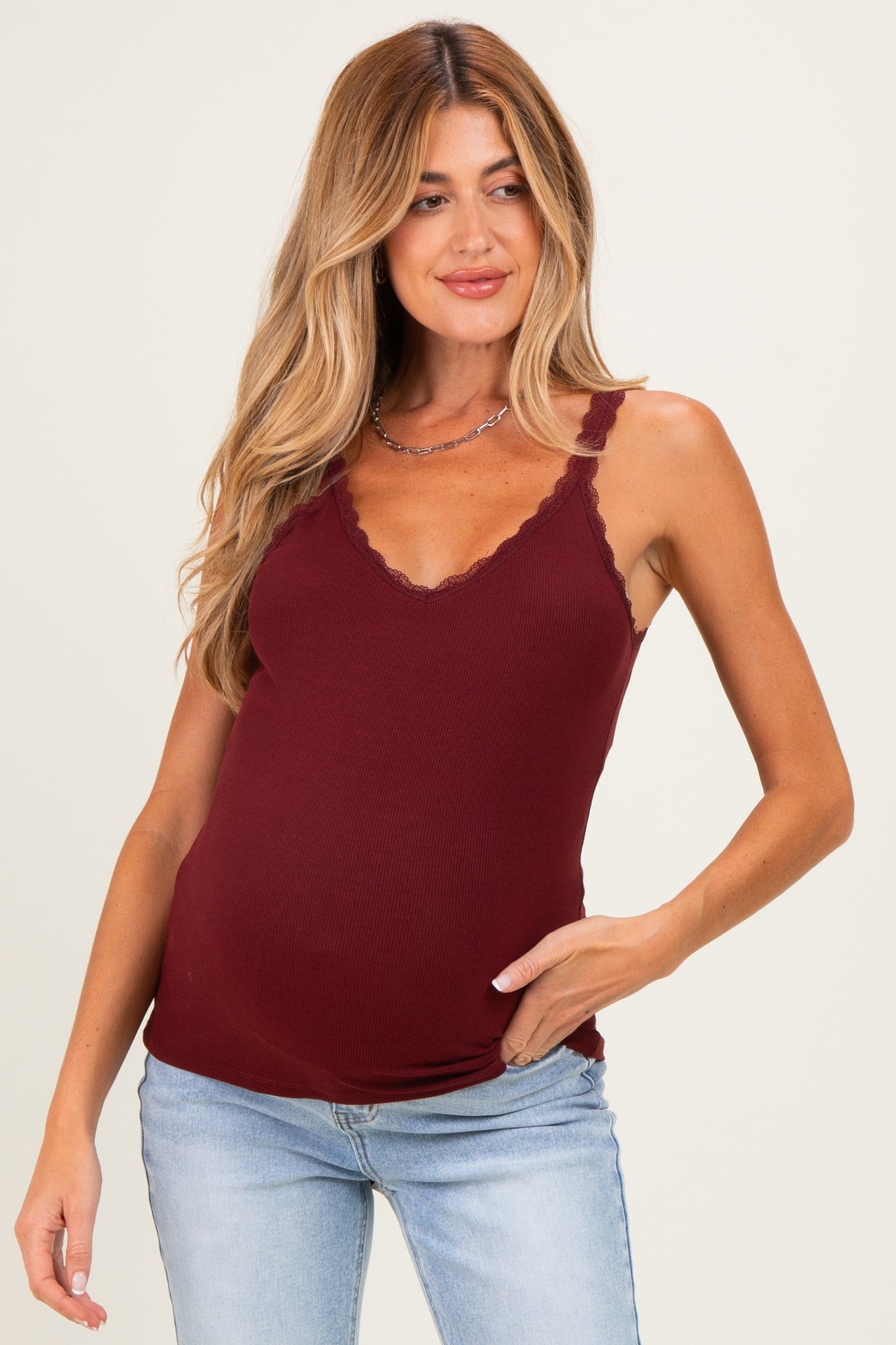 woman wearing a burgundy maternity tank top with lace trimming and a visible baby bump