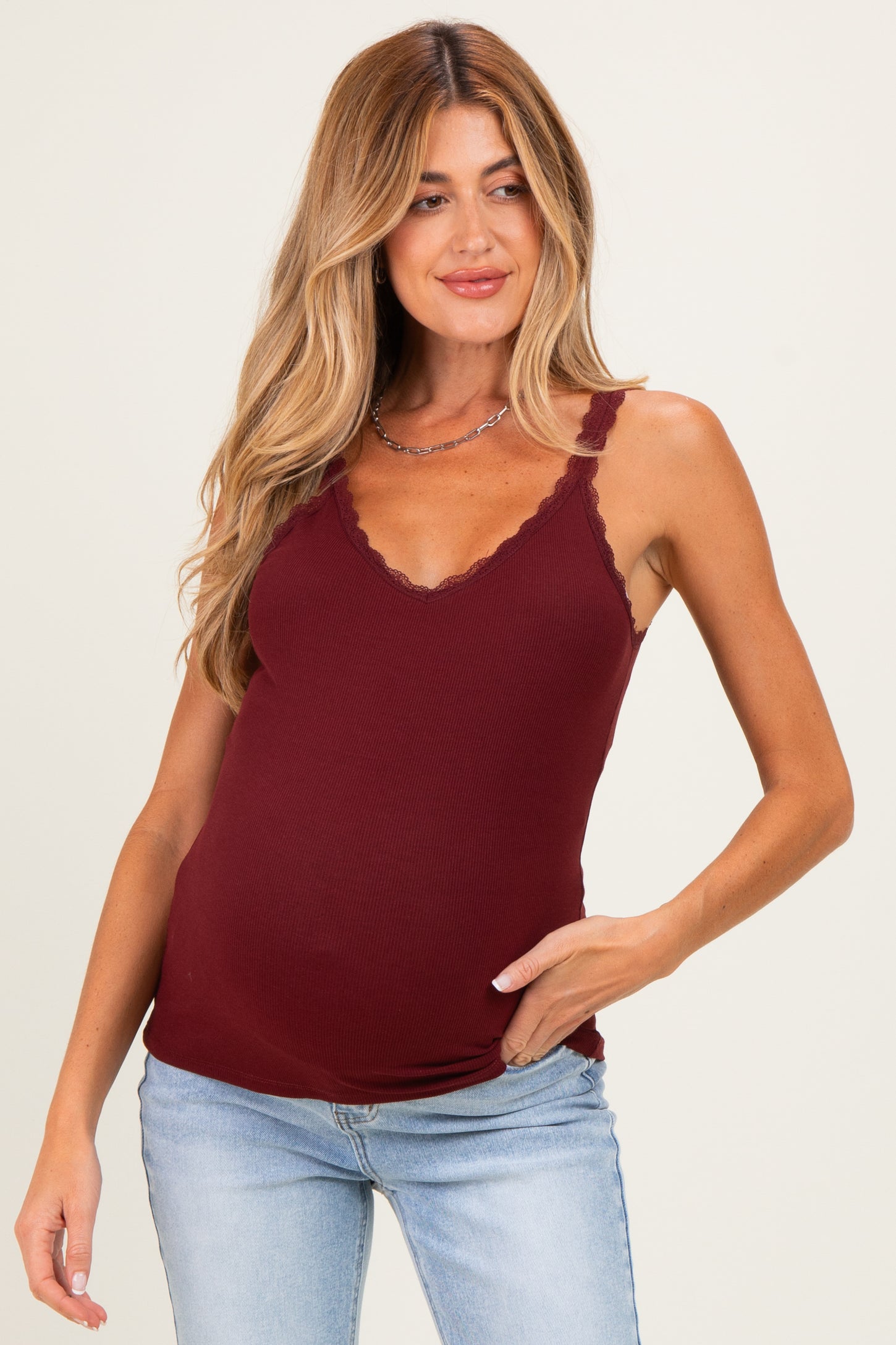 woman wearing a burgundy maternity tank top with lace trimming and a visible baby bump