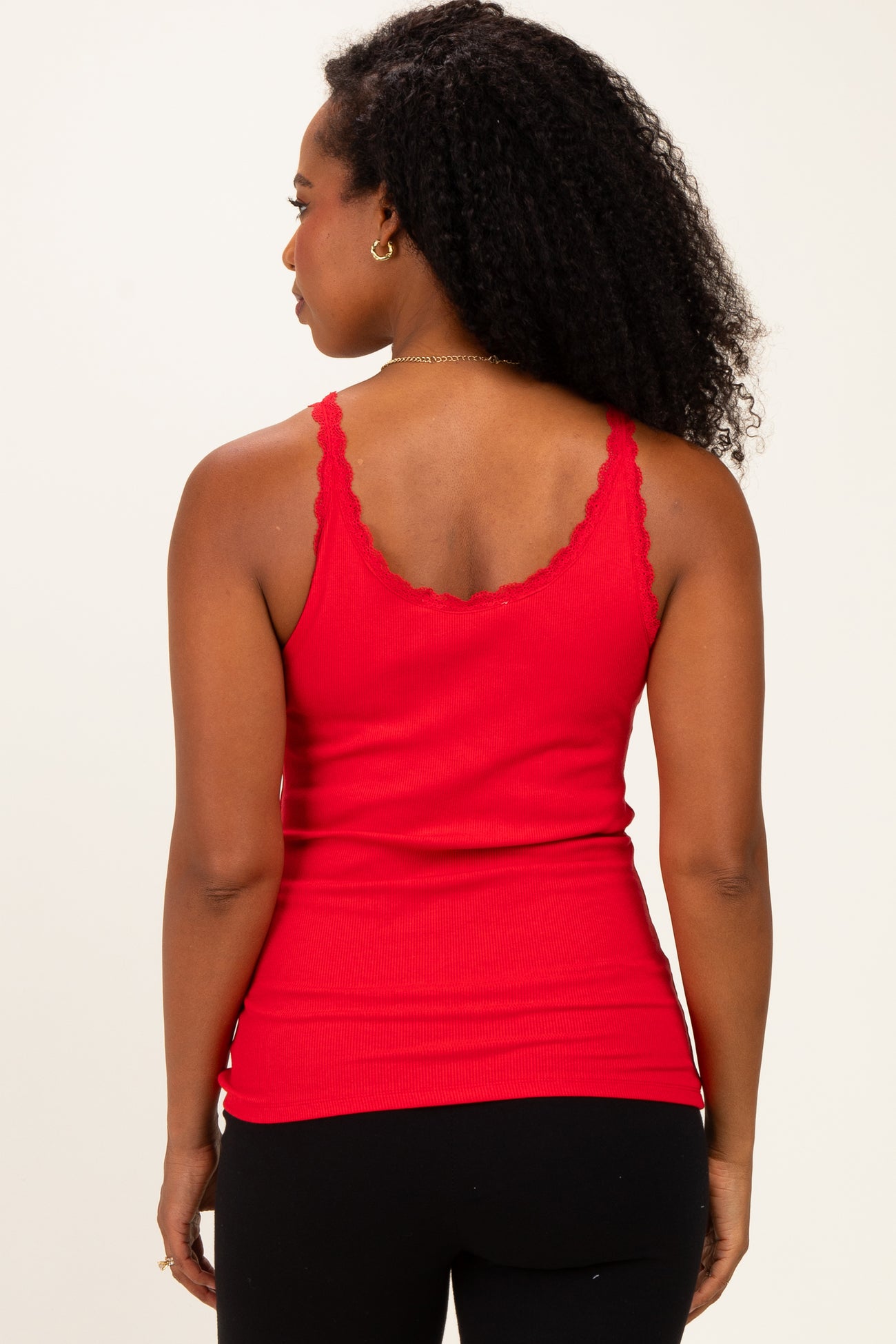 woman wearing a red ribbed tank top with scalloped edges and a fitted style, showing the back view