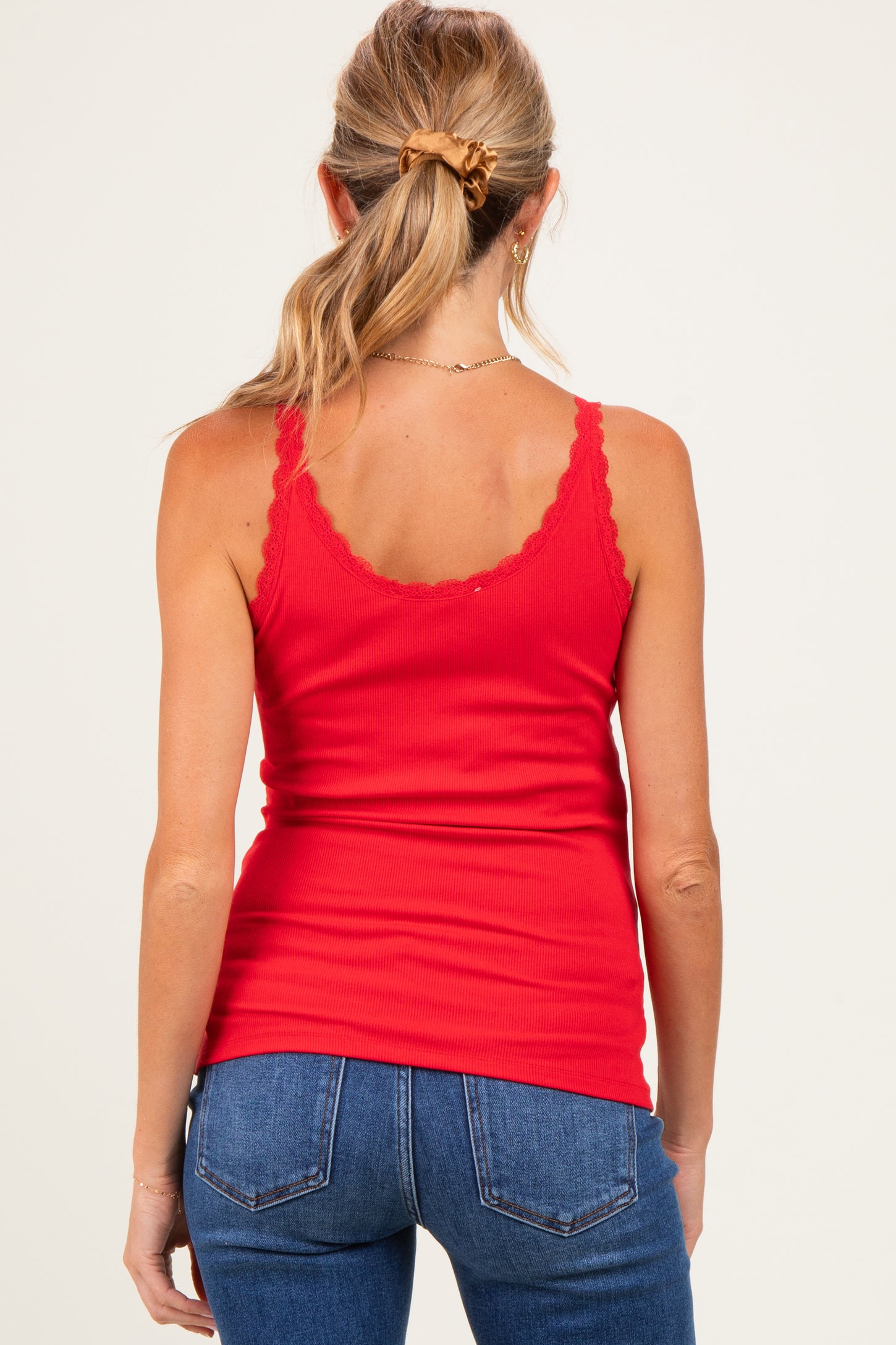 woman wearing a red maternity tank top with lace trim and back view, paired with blue jeans