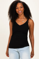woman wearing a black ribbed tank top with scalloped edges and spaghetti straps, smiling with curly hair