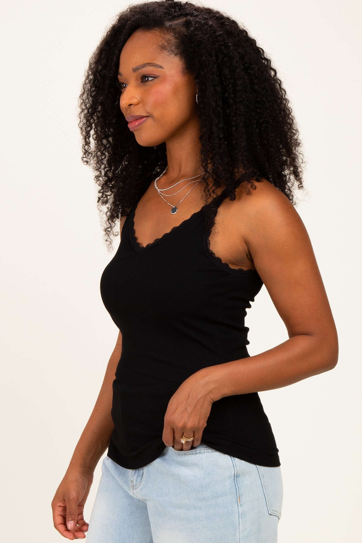 woman wearing a black ribbed tank top with lace trim and light blue high-waisted jeans