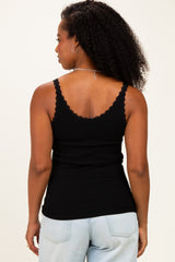 woman wearing a black scoop neck tank top with scalloped edges and spaghetti straps, viewed from the back