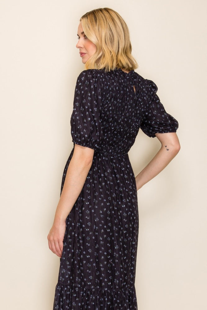 woman wearing a black floral maxi dress with puff sleeves and a smocked bodice, shown from the side