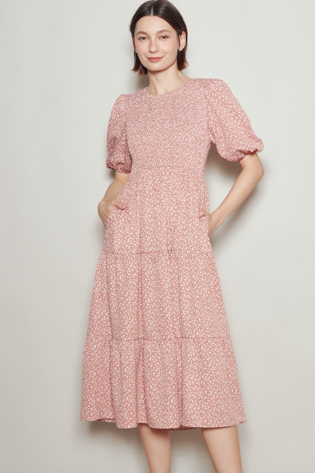 woman wearing a pink floral midi dress with puff sleeves and side pockets