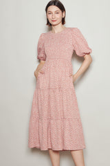 woman wearing a pink floral midi dress with puff sleeves and side pockets