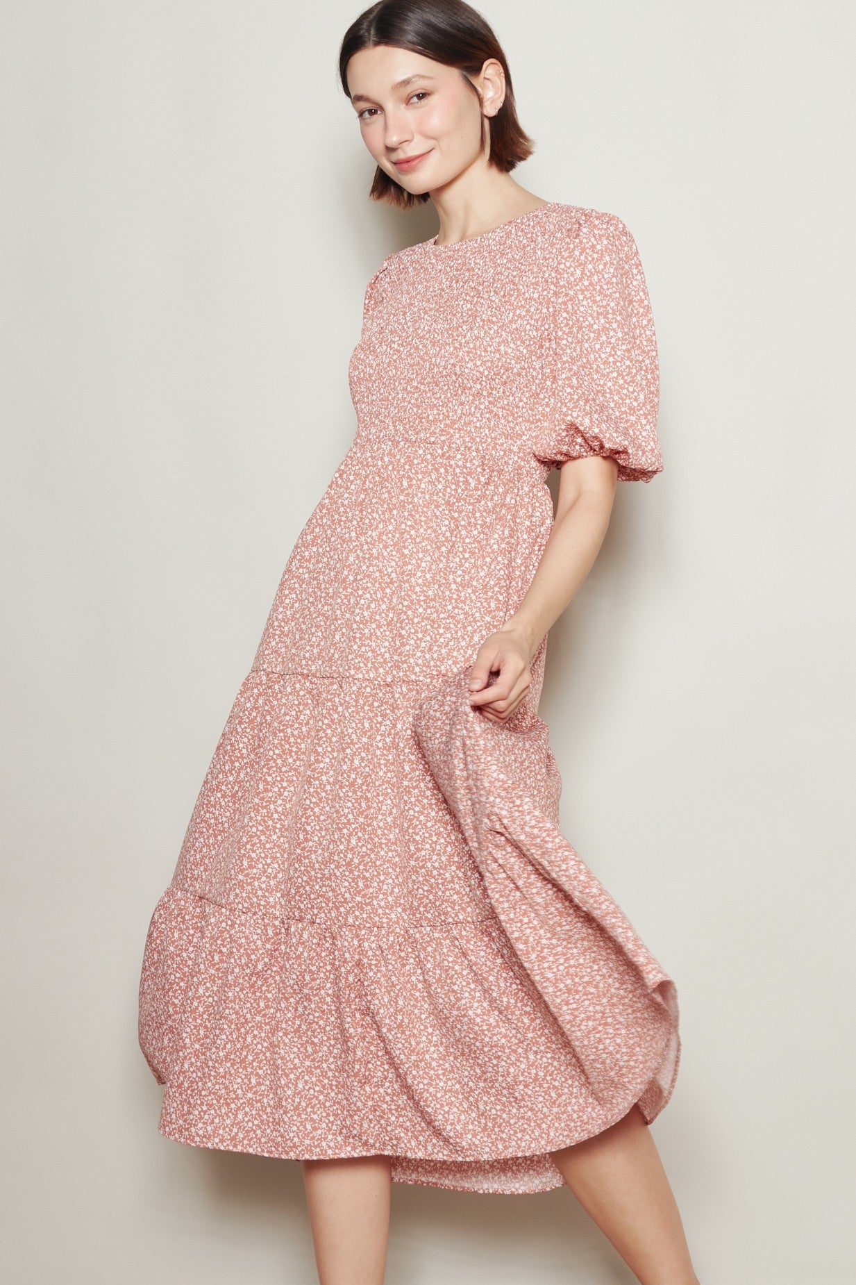 woman wearing a pink floral midi dress with puff sleeves and a tiered skirt