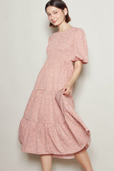 woman wearing a pink floral midi dress with puff sleeves and a tiered skirt