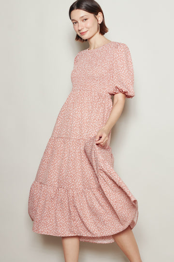 woman wearing a pink floral midi dress with puff sleeves and a tiered skirt